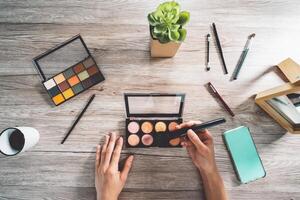 professionale trucco artista Lavorando a casa - moda bellezza influencer fabbricazione se stesso rendere su corso l'applicazione spazzola - cosmetico pubblicità concetto - di legno tavolo sfondo foto