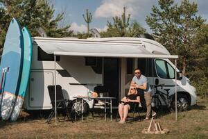 un' contento amorevole coppia è riposo vicino loro camper nel natura foto