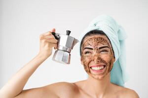 giovane sorridente donna l'applicazione caffè macchia maschera su viso - contento ragazza avendo salutare pelle cura terme giorno a casa - alternativa naturale esfoliazione trattamento e persone stile di vita concetto foto