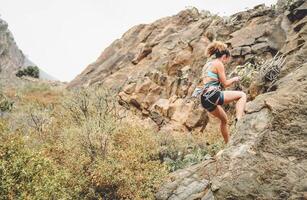 atletico donna arrampicata un' roccia parete - scalatore formazione e l'esecuzione su un' canyon montagna - concetto di estremo sport, persone Salute stile di vita e alpinismo foto