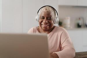 contento anziano donna avendo divertimento utilizzando un' il computer portatile nel sua Casa - tecnologia e inteligente Lavorando concetto foto