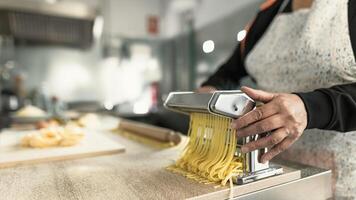 vicino su femmina mani preparazione preparazione fresco fettuccine pasta utilizzando tradizionale macchina foto