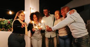 contento africano famiglia festeggiare con sparklers fuochi d'artificio a Casa festa - genitori e vacanze concetto foto