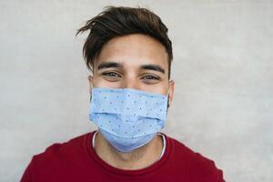 giovane uomo indossare viso maschera ritratto - latino ragazzo utilizzando protettivo mascherina per prevenire diffusione di corona virus - Salute cura e gioventù del Millennio persone concetto foto