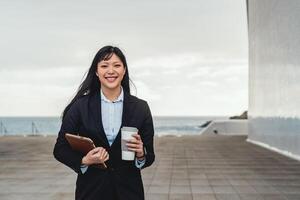 asiatico attività commerciale donna Tenere inteligente tavoletta e potabile prendere lontano caffè al di fuori ufficio - imprenditoria professionale lavoro concetto foto