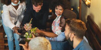 contento multirazziale amici avendo divertimento durante vacanze tostatura con cocktail e rosso vino su terrazza Casa festa - messa a fuoco su nero tipo foto