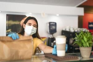 bar proprietario Lavorando solo con prendere lontano ordini durante corona virus scoppio - giovane donna lavoratore indossare viso chirurgico maschera dando pasto per i clienti - assistenza sanitaria e cibo bevanda concetto foto