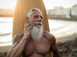 in forma anziano uomo avendo divertimento praticante Surf su tropicale spiaggia - anziano salutare persone stile di vita e estremo sport concetto foto