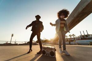 giovane afro amici indossare viso maschera danza all'aperto mentre ascoltando per musica con senza fili cuffie e Vintage ▾ Boombox foto