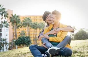 contento gay coppia nel un' romantico Data abbracciare e ridendo insieme seduta su erba nel un' parco - giovane lesbiche avendo un' tenero momento all'aperto - lgbt, bisessualità, relazione stile di vita concetto foto