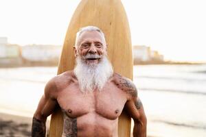 anziano in forma uomo avendo divertimento fare surf su tropicale spiaggia - anziano salutare persone stile di vita e estremo sport concetto foto