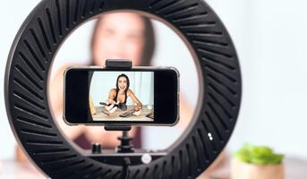 giovane femmina vlogger fare trucco lezione video per ragnatela canale a casa - contento influencer ragazza avendo divertimento le riprese con mobile smartphone - sociale media e del Millennio generazione stile di vita concetto foto