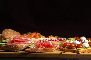 un assortimento di panini con pesce, formaggio, carne e verdure posare su il tavola e un' ciambella foto