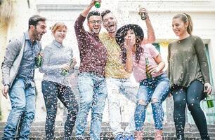 gruppo di contento amici fare festa potabile birra e lancio coriandoli - giovane del Millennio persone avendo divertimento festeggiare compleanno e ridendo insieme - amicizia, gioventù vacanze stile di vita concetto foto