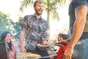 contento famiglia avendo divertimento a barbecue festa - capocuoco anziano uomo grigliate e servendo carne - fine settimana cibo bbq e riunione giovane e più vecchio persone stile di vita concetto foto