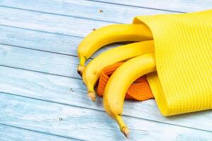 giallo banane dire bugie nel un' giallo Borsa su un' blu di legno sfondo foto