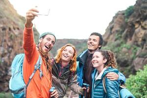 contento amici fabbricazione foto con mobile smartphone telecamera su montagna - del Millennio giovane persone il trekking e avendo divertimento con nuovo tecnologia tendenze - sport, escursionismo, Tech e sociale media concetto