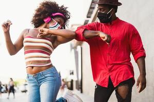 afro americano amici indossare viso protettivo maschera fare nuovo sociale distanza saluti urtando gomiti - gioventù del Millennio persone e Salute cura linee guida per evitare corona virus diffusione foto