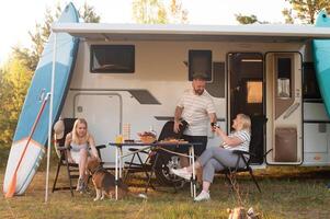 un' contento famiglia è riposo nelle vicinanze vicino loro camper nel il foresta foto