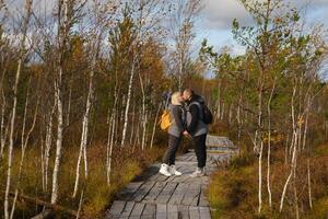 turisti con zaini bacio un' di legno sentiero nel un' palude nel Yelnya, bielorussia foto