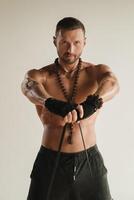 un' uomo con un' nudo torso è impegnato nel forza fitness utilizzando un' gomma da cancellare ciclo continuo in casa foto