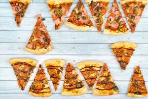 molte di delizioso triangolare Pizza fette su un' blu di legno sfondo foto