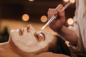 un' cosmetologo fa un' maschera per un' donna di viso per ringiovanire il pelle. cosmetologia foto