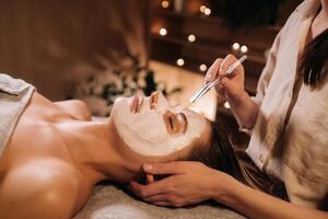 un' cosmetologo fa un' maschera per un' donna di viso per ringiovanire il pelle. cosmetologia foto