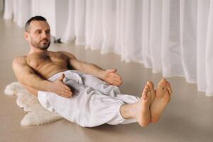 un' uomo con un' spoglio torso fa yoga nel un' fitness camera. il concetto di un' salutare stile di vita foto