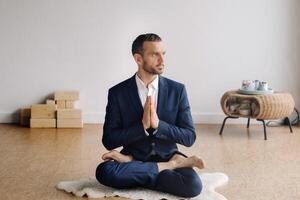 un' uomo nel un' rigoroso completo da uomo fa yoga mentre seduta nel un' fitness camera foto