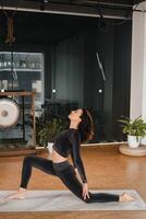 un' ragazza nel un' nero gli sport uniforme fa yoga in piedi su un' stuoia nel il Palestra foto