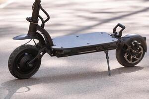 nero elettrico scooter in piedi su il in esecuzione tavola su il strada foto