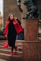 un' bellissimo elegante donna vestito nel un elegante rosso cappotto con un' elegante rosso borsetta nel il autunno città foto