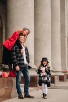 un' elegante famiglia di tre passeggiate attraverso il autunno città in posa per un' fotografo . papà, mamma e figlia nel il autunno città foto