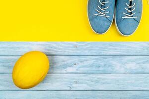 blu scarpe e un' melone In piedi su un isolato misto blu e giallo sfondo foto