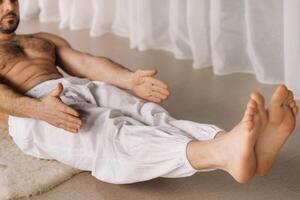 un' uomo con un' spoglio torso fa yoga nel un' fitness camera. il concetto di un' salutare stile di vita foto