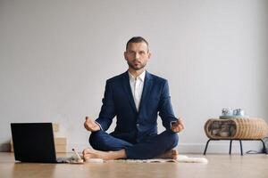 un' uomo nel un' formale completo da uomo medita mentre seduta nel un' fitness camera con un' il computer portatile foto