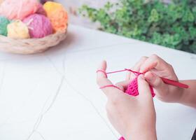 avvicinamento di donna mano maglieria con rosa lana foto