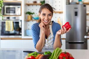 carino contento giovane brunetta donna nel bene umore preparazione un' fresco vegano insalata per un' salutare vita nel il cucina di sua casa. foto