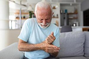 anziano uomo ha dolore nel dita e mani. vecchio uomo con dito dolore, uomo massaggio il suo artritico mano e polso. foto