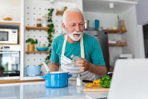 contento anziano uomo avendo divertimento cucinando a casa - anziano persona preparazione Salute pranzo nel moderno cucina - pensionato stile di vita tempo e cibo nutrizione concetto foto