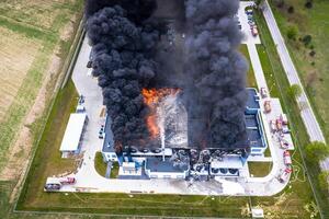 aereo Visualizza di bruciato industriale magazzino o la logistica centro edificio dopo grande fuoco con enorme Fumo a partire dal bruciato tetto foto