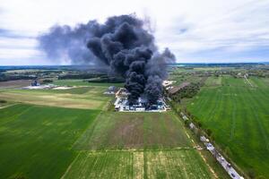 aereo Visualizza di bruciato industriale magazzino o la logistica centro edificio dopo grande fuoco con enorme Fumo a partire dal bruciato tetto foto