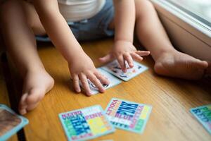 un' piccolo bambino giochi con sviluppando carte a partire dal un' tavola gioco foto
