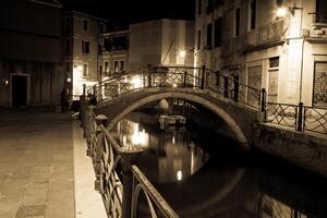 Venezia canale in ritardo a notte con strada leggero illuminante ponte e case foto