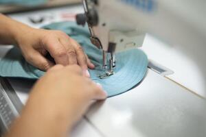 lavoratori nel un industriale indumento fabbrica cucire Abiti su cucire macchina foto