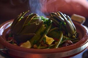 delizioso pasto con al vapore carciofi nel tagine argilla pentola. marocchino stoviglie, cultura, cucina e tradizioni foto