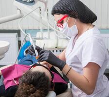 dentista l'esame denti di un' giovane donna paziente nel un' dentale clinica. odontoiatria concetto. dentista e paziente nel il dentale ufficio. foto