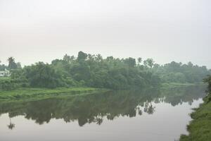 un' paesaggio Visualizza di un' calma fiume con verde alberi e montagna nel India foto