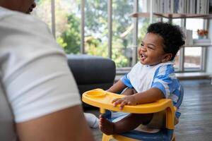 asiatico madre alimentazione sua 9 mesi vecchio sua carino poco bambino e africano americano porzione per Tenere cibo piatto a casa. foto serie di famiglia, bambini e contento persone concetto. genitori alimentazione bambini.